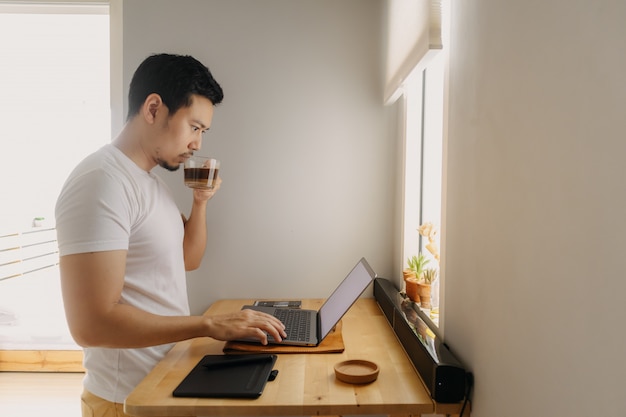 O homem do Freelancer está trabalhando em seu laptop em seu apartamento. Conceito de trabalhos criativos freelance.