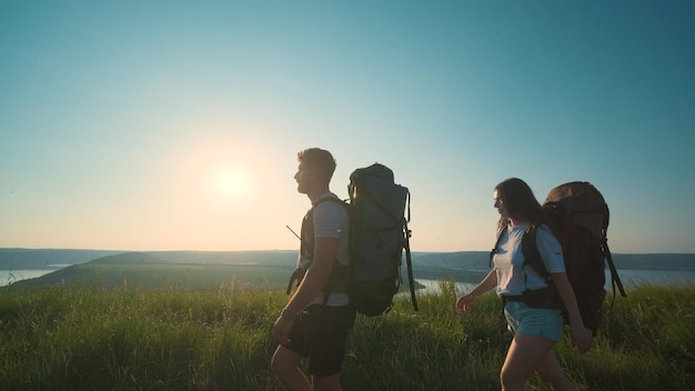 O homem e a mulher andando com mochilas em um fundo de céu azul