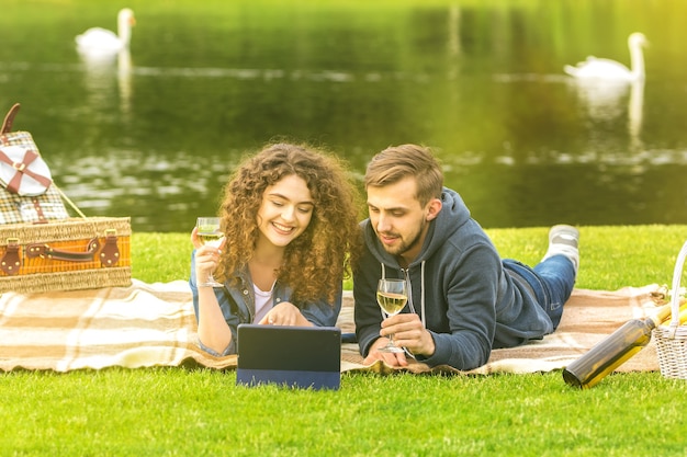 O homem e a mulher bebem um vinho perto do rio