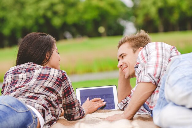 O homem e a mulher com um tablet deitados no chão