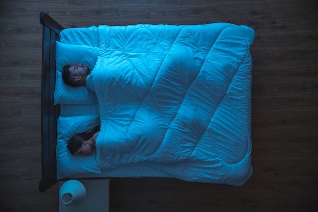 O homem e a mulher dormindo na cama. período noturno. vista de cima