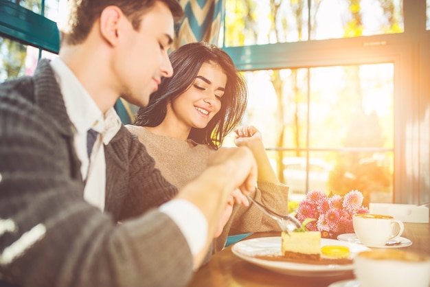 O homem e a mulher felizes comendo a sobremesa no café