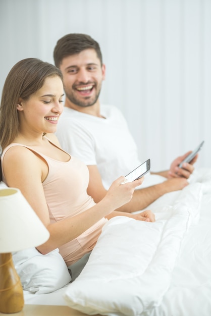 O homem e a mulher sentam e telefonam na cama