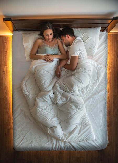 Foto o homem e uma mulher dormindo na cama. vista de cima