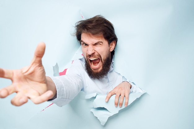 O homem emocional estende a mão para frente olhando através da parede do escritório de emoções