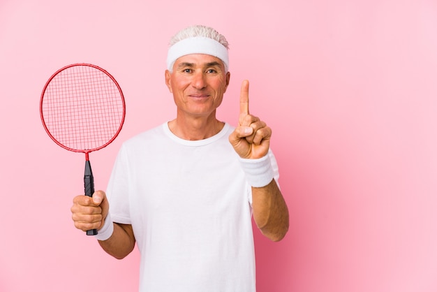 O homem envelhecido médio que joga o badminton isolou mostrar o número um com dedo.