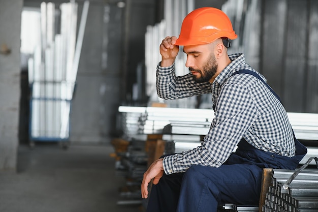 O homem escolhe o perfil do metal para a construção na fábrica