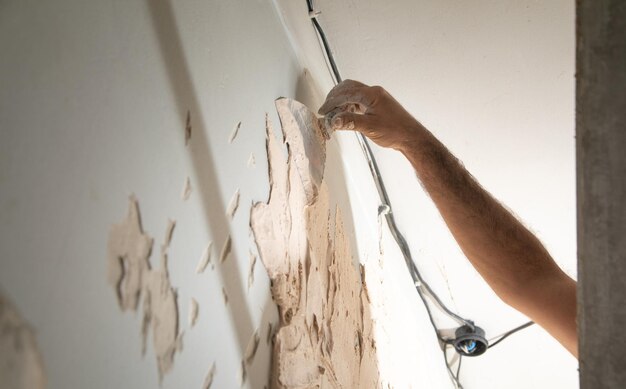 O homem está aplicando massa em uma parede Renovando a casa