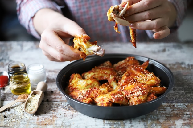 O homem está comendo asas de frango. Asas de frango frito.