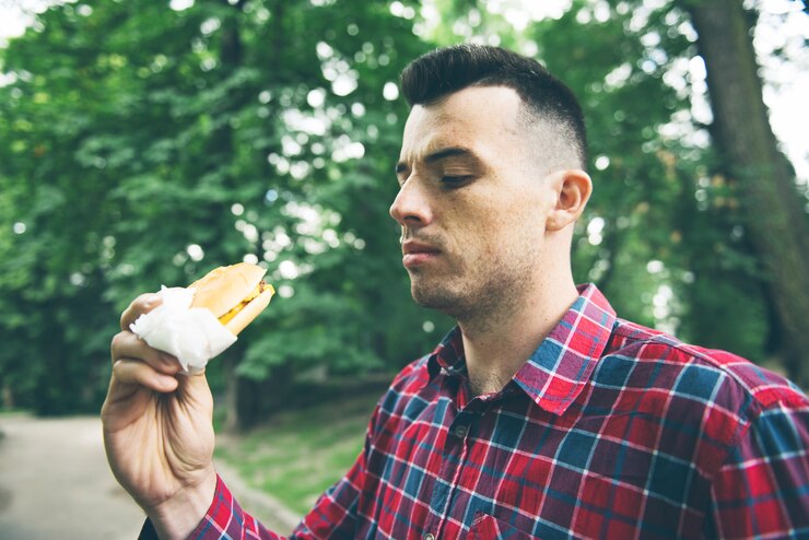 Foto o homem está comendo no parque e saboreando uma comida deliciosa
