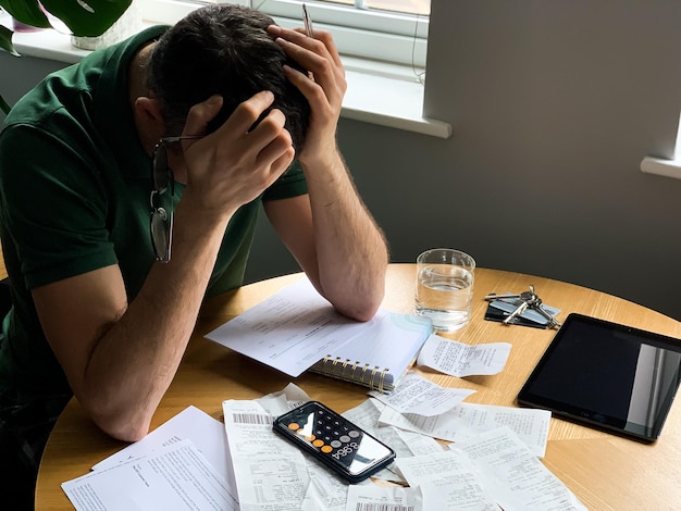 Foto o homem está fazendo auditoria de despesas domésticas usando calculadora e caderno muitos recibos e contas