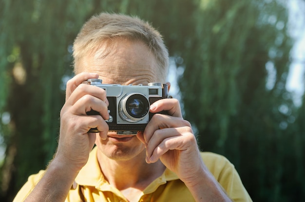 O homem está fotografando uma câmera antiga.