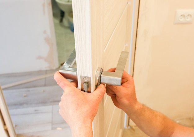 O homem está instalando a maçaneta das portas Trabalhos de reparo Manutenção no apartamento