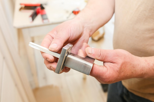 O homem está instalando a maçaneta das portas Trabalhos de reparo Manutenção no apartamento