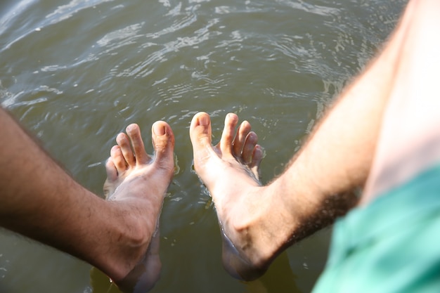 O homem está lavando as pernas na água. Vibes do verão.