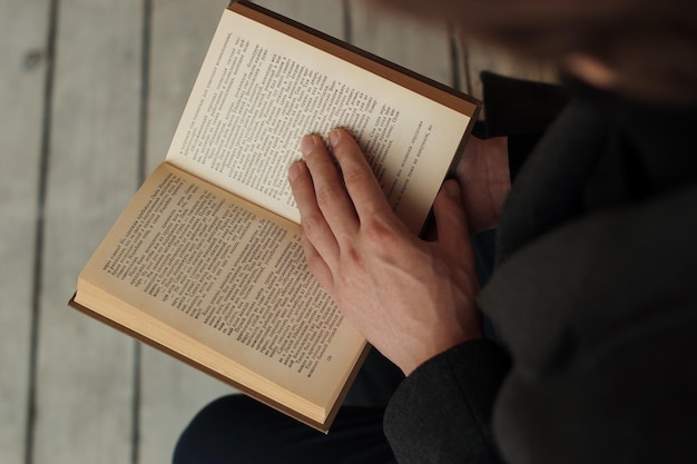 Foto o homem está lendo um livro de capa dura vista de cima para baixo das mãos masculinas no livro aberto