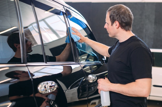 o homem está limpando com o corpo de pano de um carro brilhante.