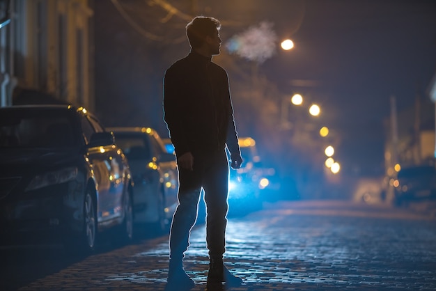 O homem está na estrada de pedra. Noite à noite. Foto com lente telefoto