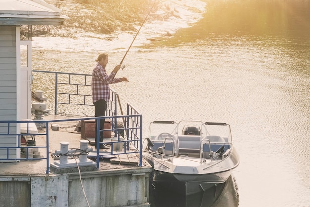 O homem está pescando na doca perto do barco