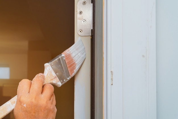 O homem está pintando a porta com escova