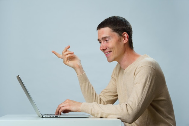 O homem está sentado à mesa e usando o laptop para comunicação em bate-papo ou bate-papo por vídeo Conceito de mídia social