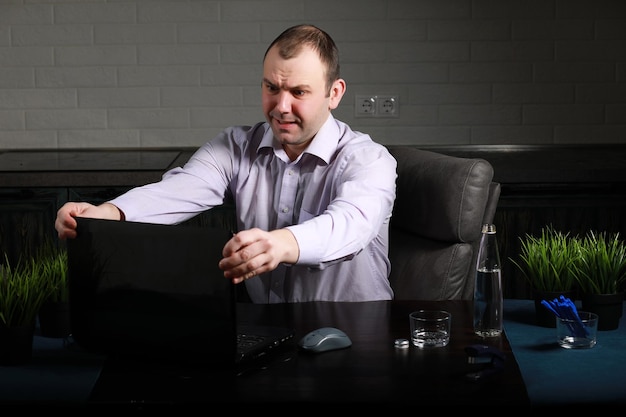 O homem está sentado em sua mesa e trabalhando em um laptop