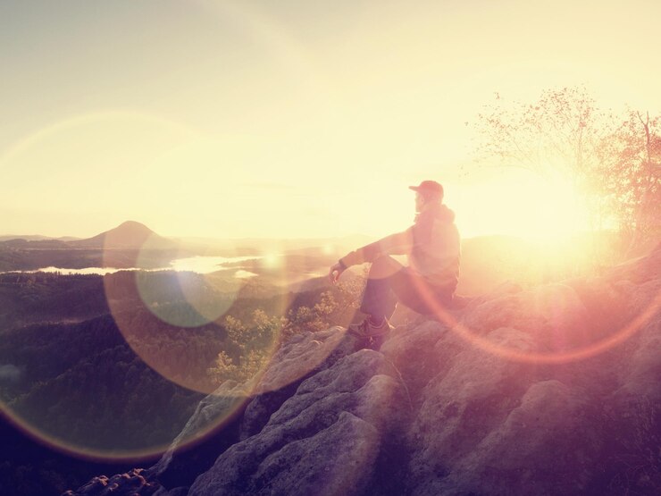 Foto o homem está sozinho no pico da rocha caminhante observando o sol de outono no horizonte belo momento