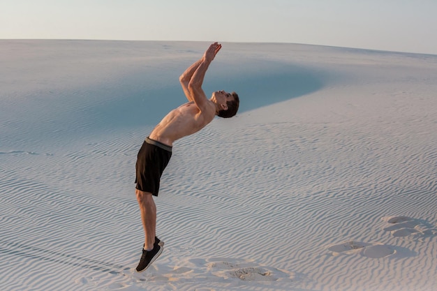 O homem estuda parkour por conta própria. Acrobacia na areia