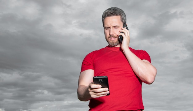 Foto o homem fala ao telefone, veste uma camiseta vermelha com a foto do anúncio do espaço da cópia do homem fala ao telefone