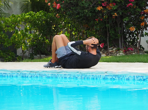 O homem faz um exercício de imprensa perto da piscina