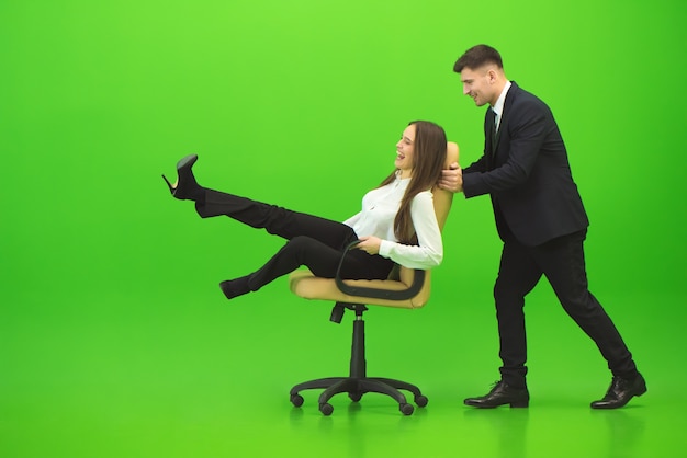 O homem feliz e a mulher se divertem na cadeira sobre o fundo verde