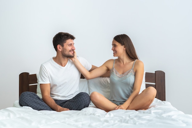 O homem feliz e uma mulher sentada na cama, no fundo branco