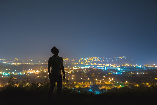 O homem fica no fundo das luzes da cidade. período noturno