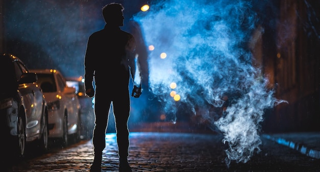 O homem fuma na rua Noite à noite Tiro de lente telefoto