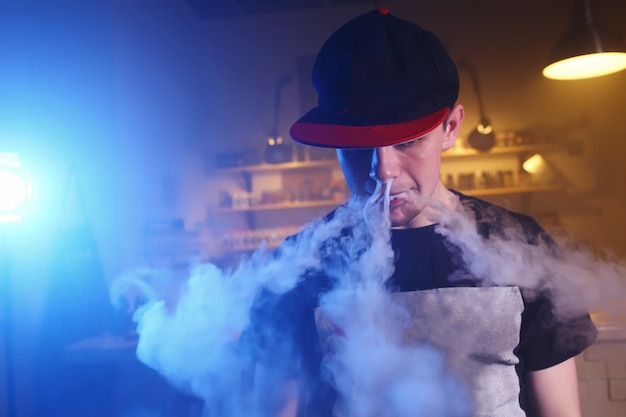 O homem fuma um cigarro eletrônico na loja vape