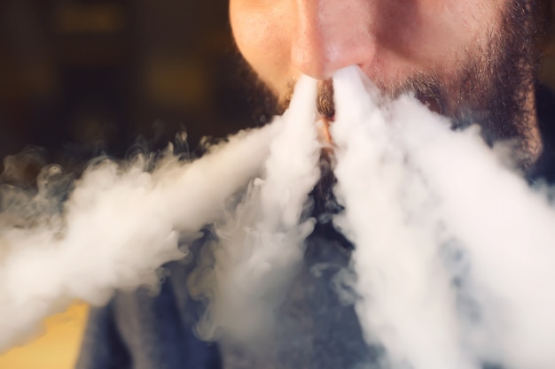 O homem fuma um cigarro eletrônico na loja vape