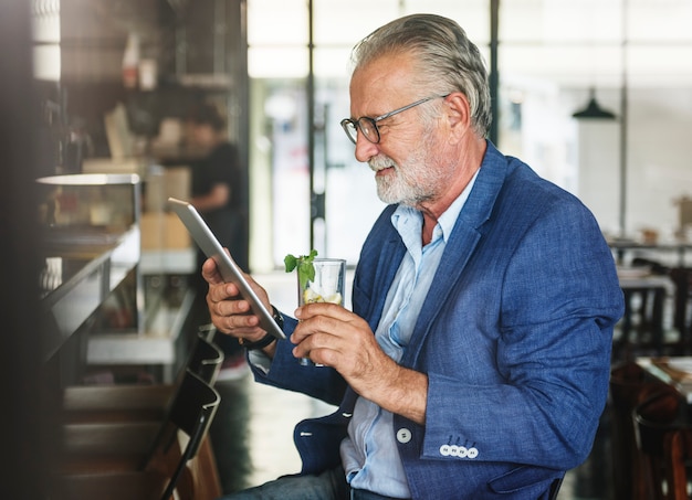 O homem idoso está usando tablet digital