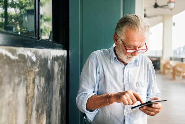 O homem idoso está usando tablet digital
