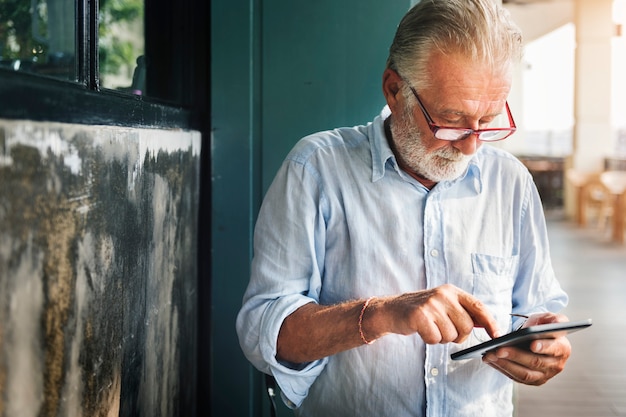 O homem idoso está usando tablet digital