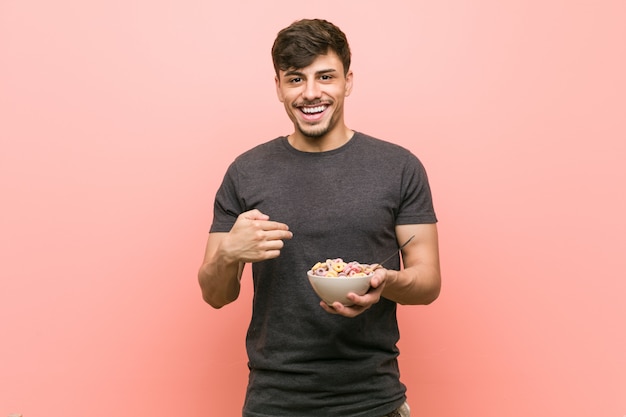 O homem latino-americano novo que guarda uma bacia de cereal surpreendeu apontar-se, sorrindo amplamente.