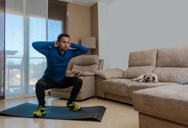Foto o homem latino, fazendo exercícios na sala de estar, faz abdominais, alongamentos e agachamentos