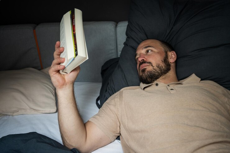 Foto o homem lê um livro de fantasia na cama.