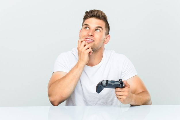 O homem novo que guarda um controlador de jogo relaxou o pensamento sobre algo que olha um espaço da cópia.