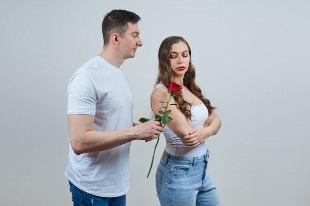 O homem pede perdão à loira ofendida, dá a ela uma rosa vermelha.
