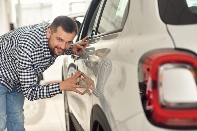 O homem pensa em um novo modelo de gama de carros e tenta escolher o melhor para si.