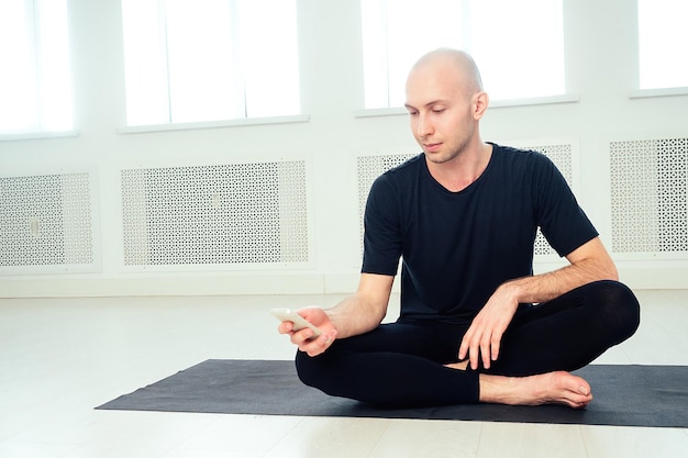 O homem pratica ioga e faz selfie no telefone no estúdio. asanas matinais na aula de ioga