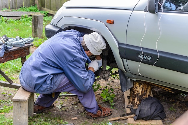 O homem repara o carro no campo