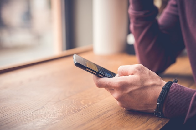 O homem segura um telefone perto da janela