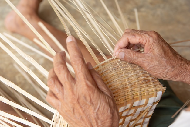 Foto o homem sênior entrega manualmente o bambu de tecelagem.