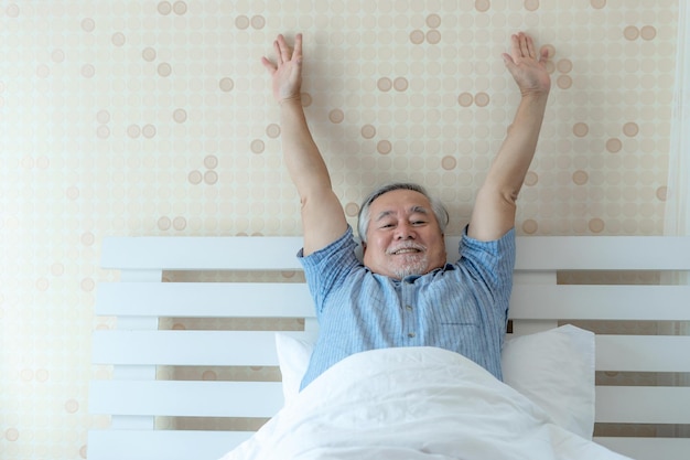 O homem sênior sente-se feliz e com boa saúde, acorda de manhã aproveitando o tempo em seu quarto interior em casa, estilo de vida, conceito de felicidade sênior